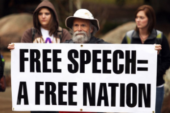 A man holds a sign saying “Free speech = a free nation” at a free speech rally. Source: Wikimedia Commons