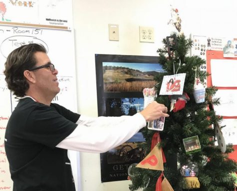 Mike Muhovich puts a student's ornament on the Christmas Tree. Photo by Jamie Ma.