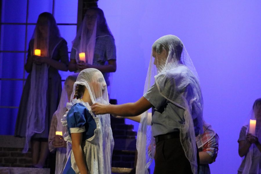 Sophomores Emma Hill and Nate Baesel cover themselves in white cloaks during a performance. Photo by Jose Perez