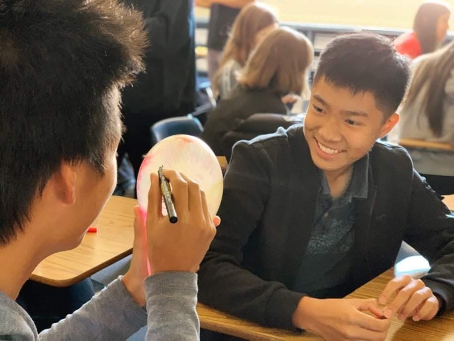 Senior Nicholas Caluyas friend drawing a self portrait of him on a balloon. Photo courtesy of Nicholas Caluya. 