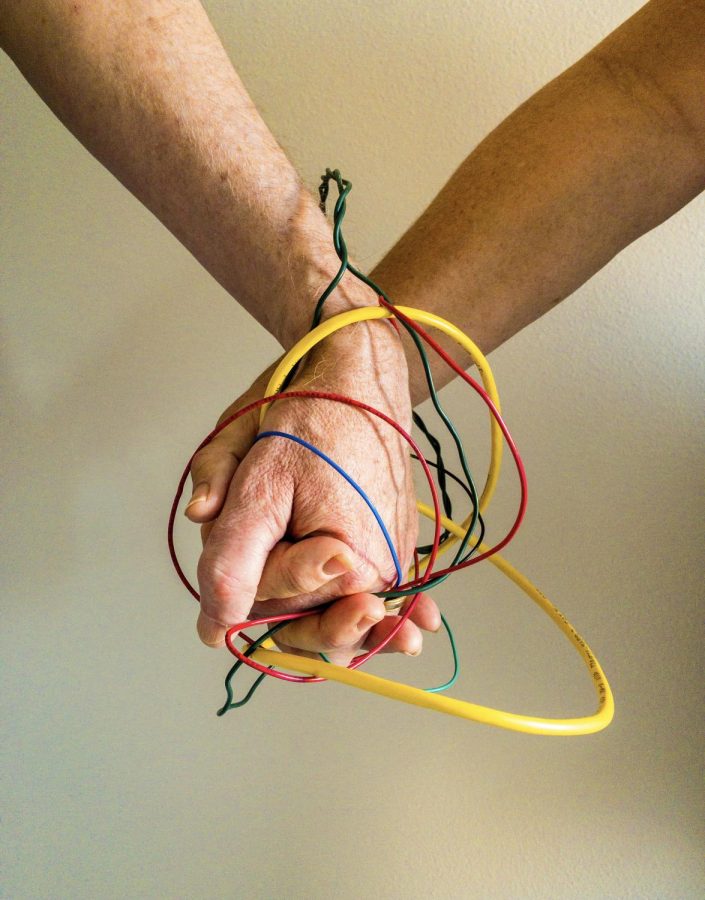 Senior Delaney Spillane’s project shows that relationships, either friendly and romantic, can be strengthened by the virtual world. In other words, social media and text messaging can be positive relationship-building tools.
Spillane took a photo of her parents holding hands. “The colorful wires represent technology and show that tech can bring people together,” she said.