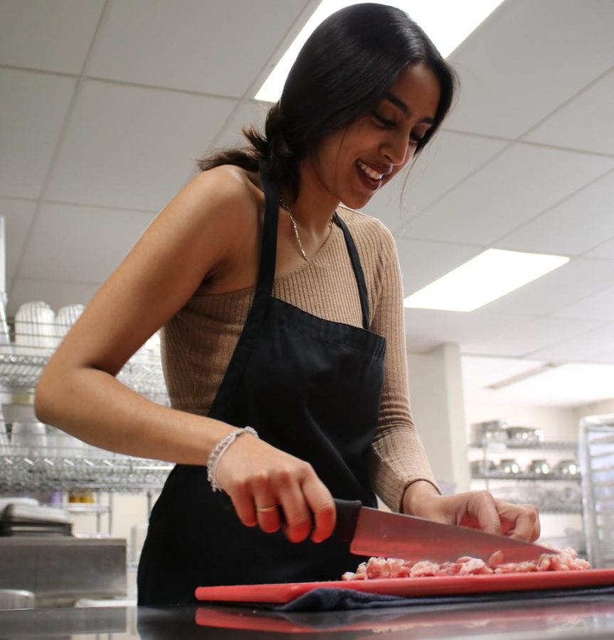 Senior Harmony Oberoi cuts bacon during her fourth period culinary class.