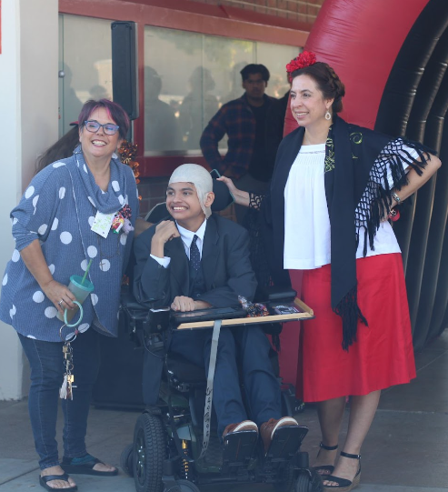 Photography teachers Gabby Kudron and Maggie Crail pose with senior Joseph Lopez who won the Halloween Parade held at break as Professor X from the Marvel series X-Men.