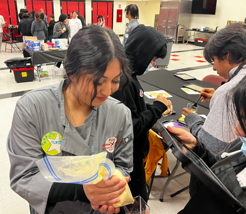 Senior Leslie Eduviges shows a student how to pipe frosting. FUHS Culinary and Hospitality students traveled to Commonwealth Elementary on Feb. 6 to mentor elementary school students on proper food preparation and kitchen safety. 