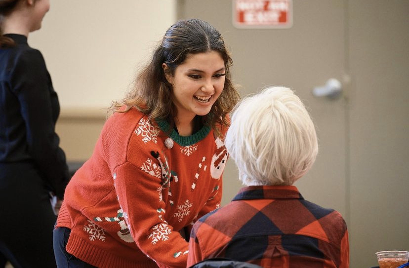 Senior Madison Heinle speaks to an audience member at the choral program’s annual Holiday Luncheon with the Fullerton Ebell Club.
