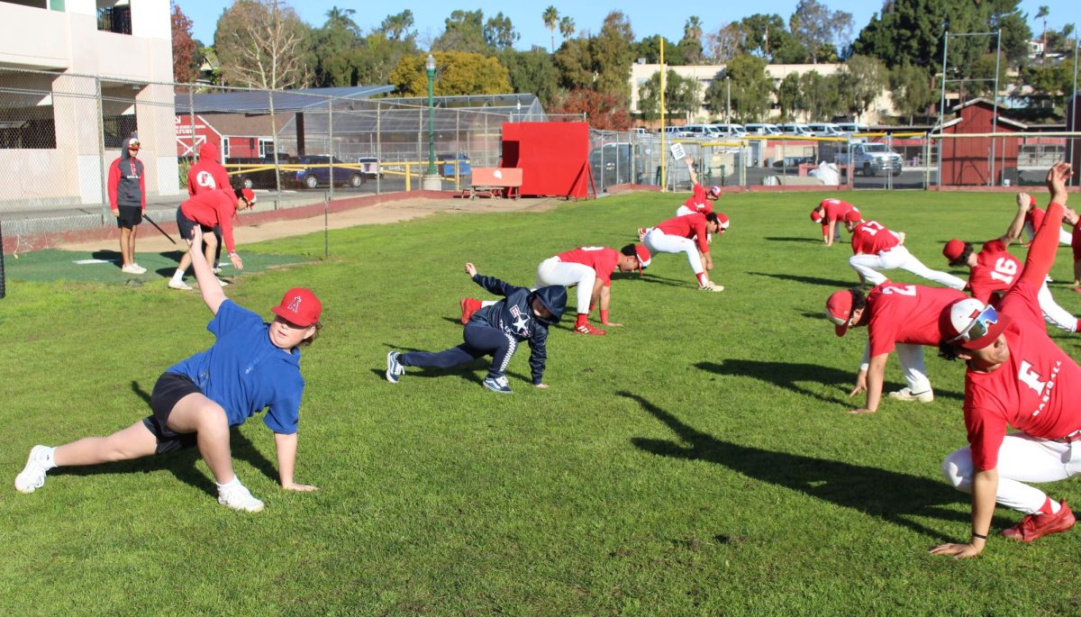 Mikah Carney (center) and his brother (left) stretch with the baseball team before their game.