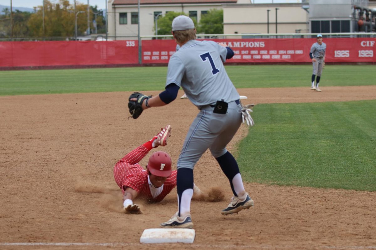 Junior Malachi Meni slides safely into third base as he hits a triple against the Raiders.