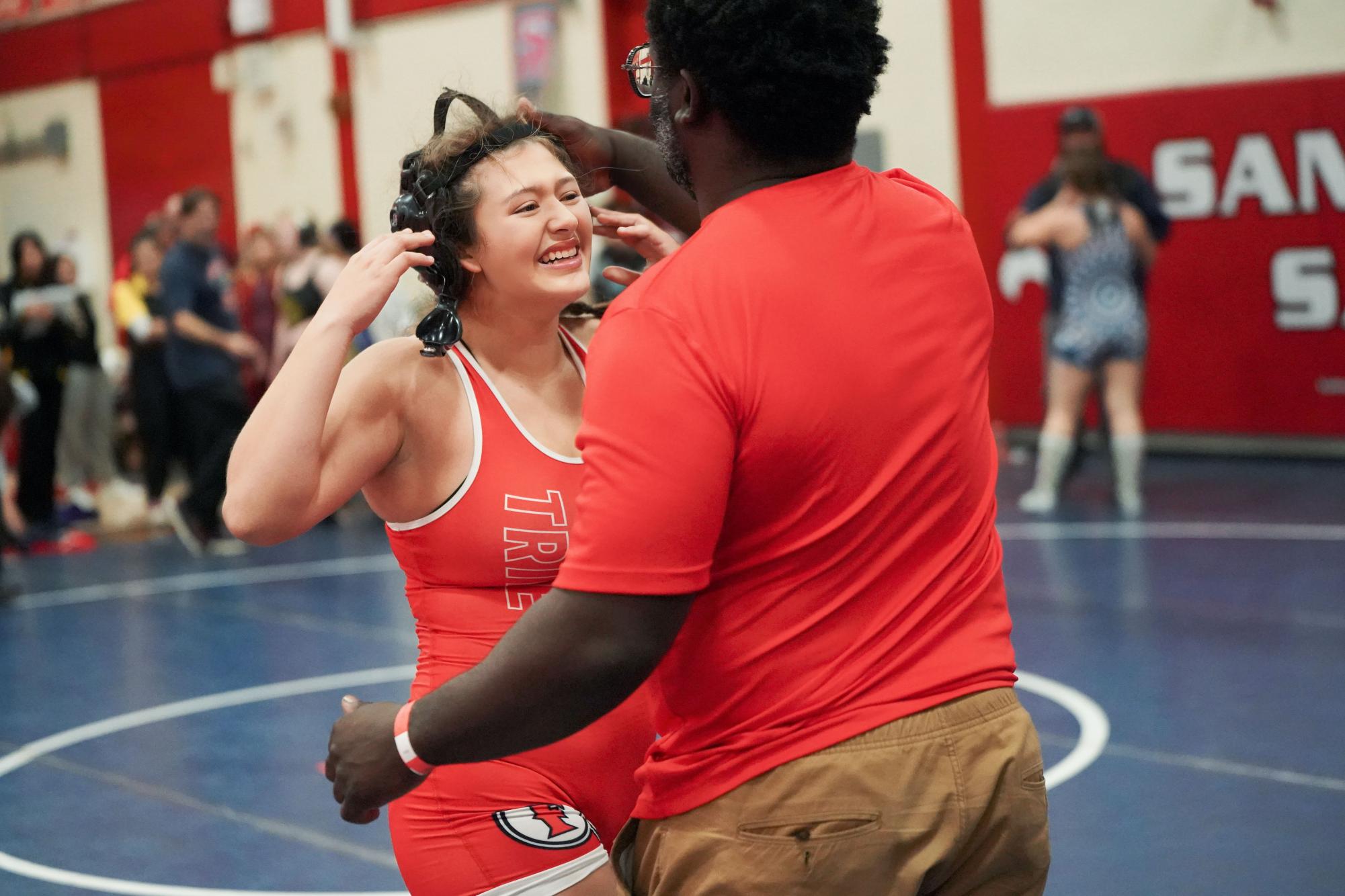 Levi Burrell and her wrestling coach, Jayson Baxter, celebrates her win from a match in CIF.