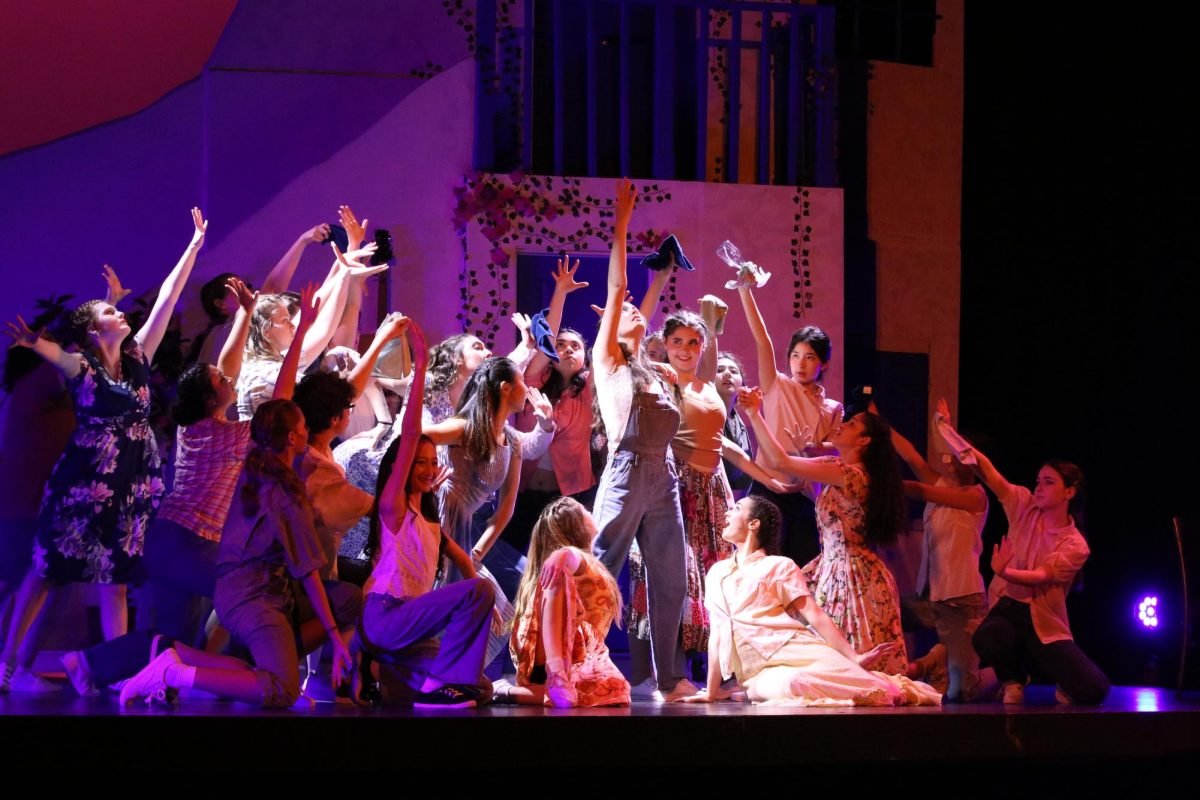 There are a lot of ensemble vocals in Mamma Mia. The musical was written Broadway-level click tracks in mind, to cue background vocals remotely and play pre-recorded tracks. Music director Stacey Kikkawa wanted live singing rather than pre-recordings, so she created a system called “the shoe rack.” She split the cast into nine groups, each named after a style of shoe, ranging from go-go-boots to birkenstocks. Huddled around multiple microphones backstage, the shoe groups sing backup vocals. 