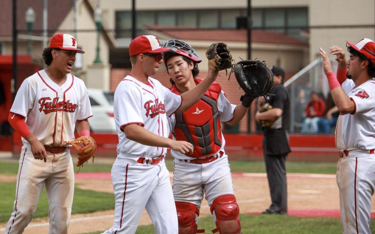 Teammates high-five senior Wayne Warden after scoring a run against Calvary Chapel. Photo by Madison Sibal
