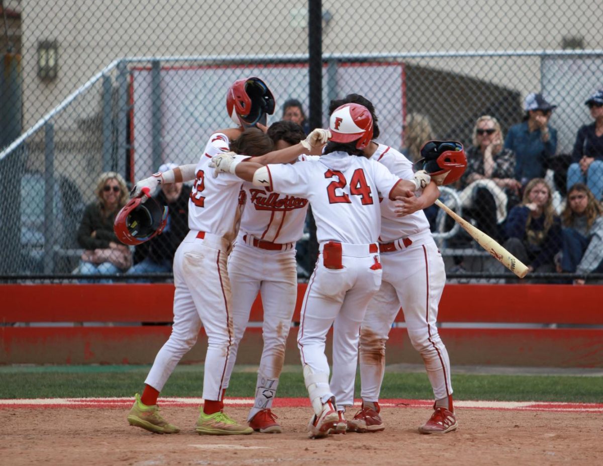 (From left to right) Sophomore Samuel Chacon, senior Zach Fany and junior Caleb Brown celebrate senior Christian Robinson after his home run. Photo by Madison Sibal