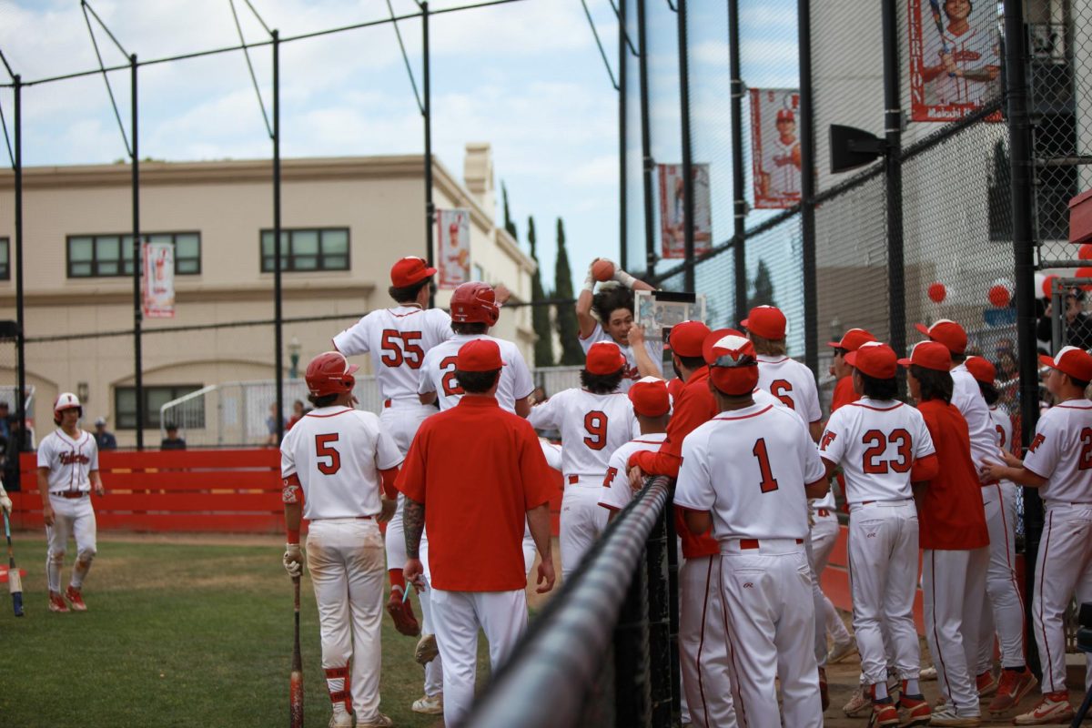 The dugout runs out with a miniature basketball and hoop to celebrate senior Christian Robinson's home run. Photo by Madison Sibal