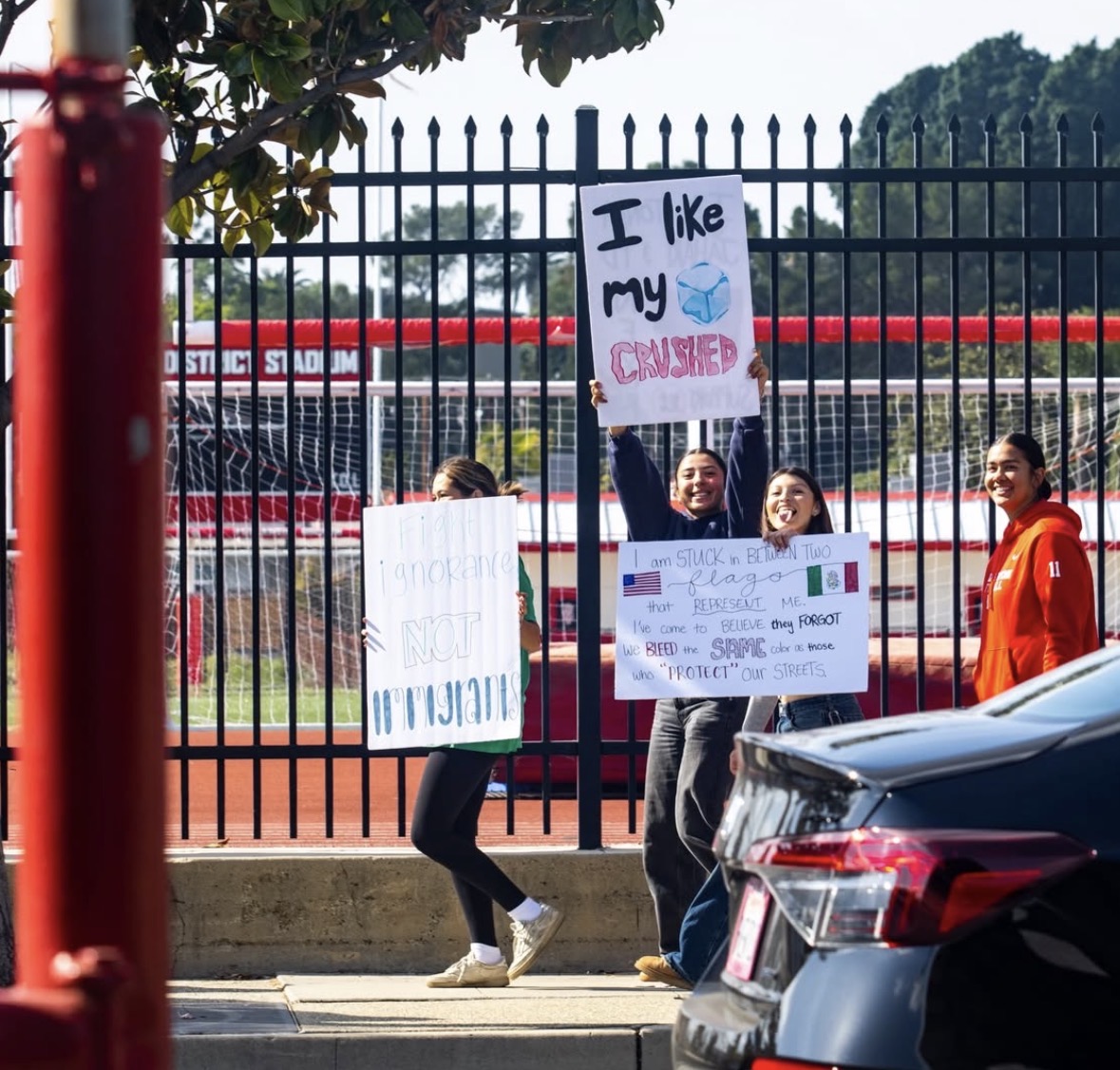 Students holding up protest signs outside of FUHS football stadium.
