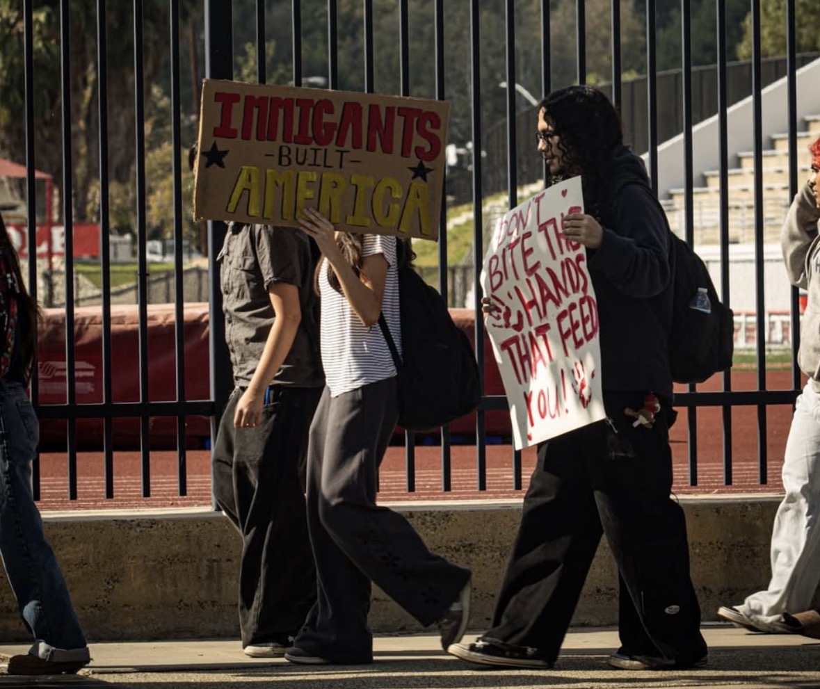 Protestors hold up signs to support immigrants during the walkout.