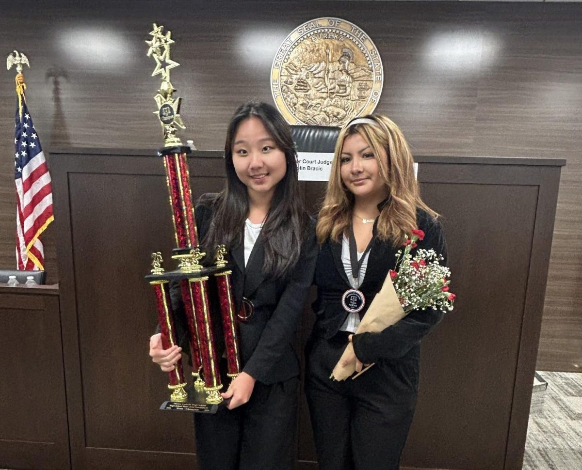 Senior Jane Kwak (left) and senior Camila Cruz (right) hold the first place trophy after winning the JSerra Mock Trial Tournament Championship against Troy High School.